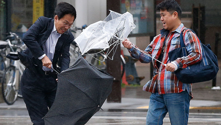 Жители Токио во время сильного ветра на одной из улиц города