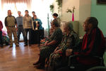 Бабушки и дедушки из дома престарелых в Бегичево слушают выступление волонтеров