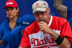 Участник конкурса по поеданию хот-догов на скорость в Нью-Йорке, 4 июля 2023 года