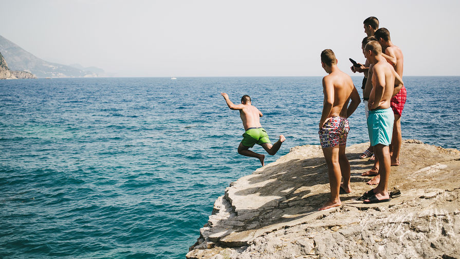 Отдыхающие прыгают со скалы недалеко от пляжа Могрен в Будве, Черногория