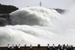 Туристы наблюдают процесс регуляции уровня воды на плотине Сяоланди, которая перекрывает реку Хуанхэ, Китай, 25 июня 2023 года