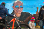 Прохожие у портрета президента России Владимира Путина на стене здания в Ялте