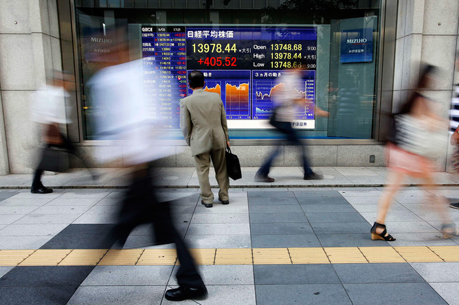 Японец возле информационного табло биржи Nikkei в Токио