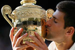 Новак Джокович целует кубок после победы над Роджером Федерером