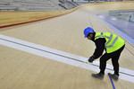 Рабочий устанавливает ленту на финишную черту олимпийского велодрома в Стрэтфорде