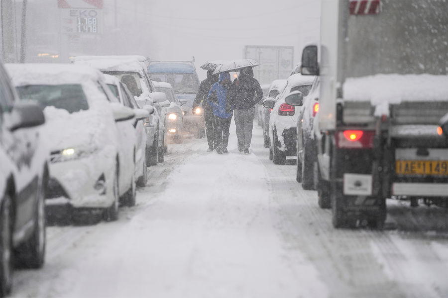 Люди идут пешком вдоль проезжей части во время сильного снегопада в&nbsp;Афинах, Греция, 24&nbsp;января 2022&nbsp;года