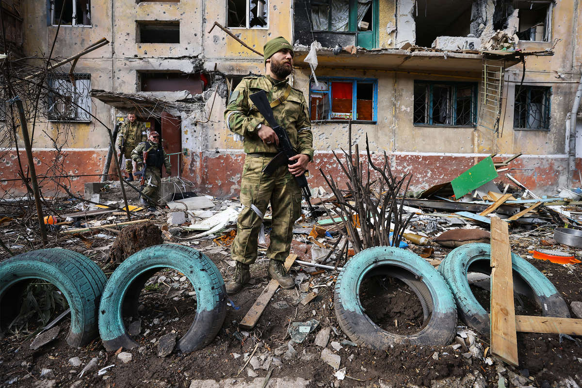 Участник добровольческого отряда из Южной Осетии у разрушенного дома в Мариуполе, 22 апреля 2022 года
