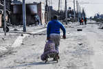 A man in the Zhovtnevy district of Mariupol pushes sacks of potatoes into a car, March 2022