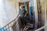 Жительница Славянска выходит из своей разрушенной попаданием снаряда квартиры