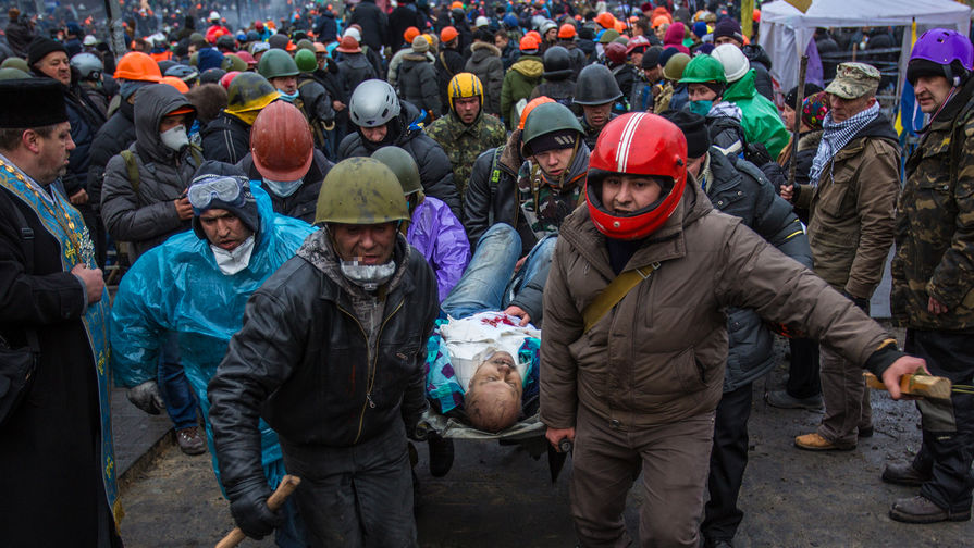 Сторонники оппозиции несут раненного во время столкновений с сотрудниками правопорядка на площади Независимости в Киеве, 20 февраля 2014 года