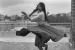 Итальянская актриса Клаудия Кардинале в рубашке и широкой юбке танцует босиком на террасе на крыше в Риме, 1959 год