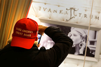 Мужчина в кепке с предвыборным лозунгом Дональда Трампа около витрины ювелирного магазина Иванки Трамп в Нью-Йорке, декабрь 2016 года