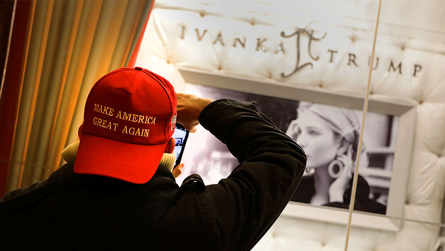 Мужчина в кепке с предвыборным лозунгом Дональда Трампа около витрины ювелирного магазина Иванки Трамп в Нью-Йорке, декабрь 2016 года