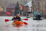 Люди в лодке на затопленной улице в микрорайоне Кузнечный в Оренбурге, 10 апреля 2024 года