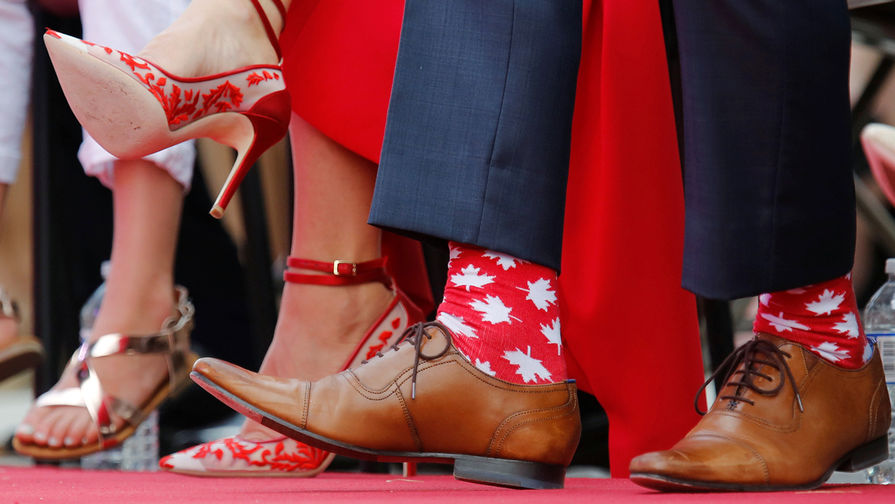 Премьер-министр Канады Джастин Трюдо в носках c кленовыми листьями под флаг страны в День Канады, 1 июля 2016 года 