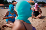 6 июля. Китаянки в нейлоновых масках, защищающих от солнечных лучей, на пляже в Циньдао, провинция Шаньдунь.