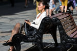 Девушка отдыхает под солнцем на Никольской улице в Москве, 18 мая 2021 года