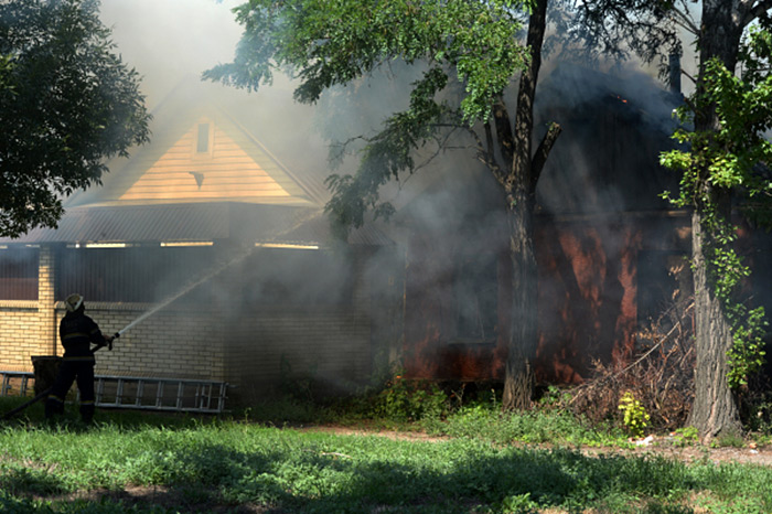 Сотрудники МЧС тушат пожар в частном доме, пострадавшем во время артиллерийского обстрела города украинской армией