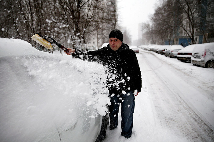 Житель города очищает автомобиль от снега на&nbsp;одной из&nbsp;улиц города.