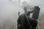 Статуя в дыму от факелов во время протеста демонстрантов у парижской ратуши, 14 апреля 2023 года