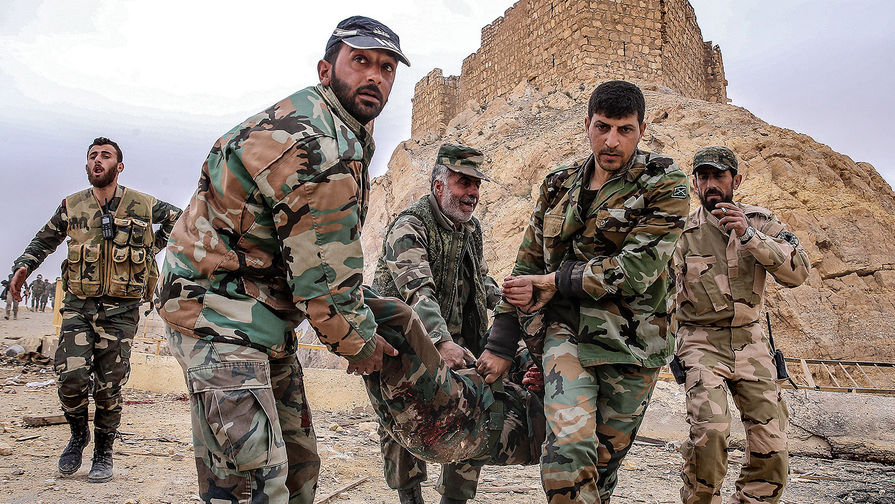 Бойцы сирийской армии несут раненого у&nbsp;подножия замка Фахр ад-Дина