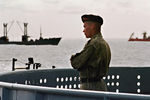Российский моряк на борту ракетного крейсера «Петр Великий» во время спасательной операции на месте крушения АПЛ «Курск» в Баренцевом море, 21 августа 2000 года. На заднем плане российское судно «Михаил Рудницкий» и норвежское Normand Pioneer