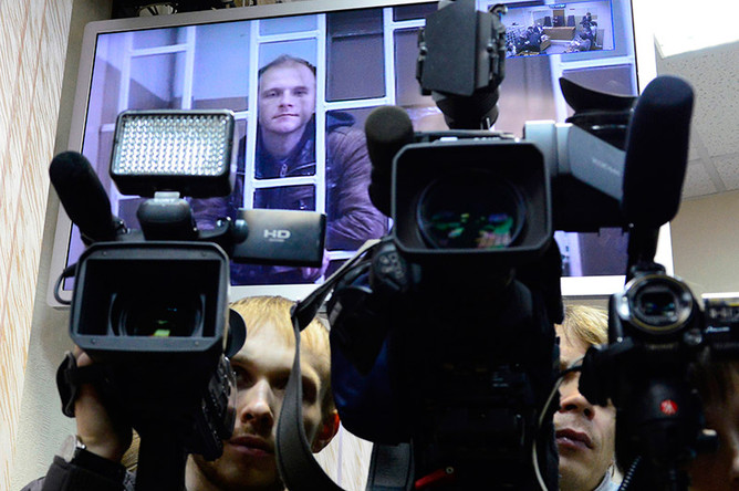Фотограф Денис Синяков (на экране), обвиняемый в незаконной попытке проникновения на платформу «Приразломная», во время рассмотрения апелляции
