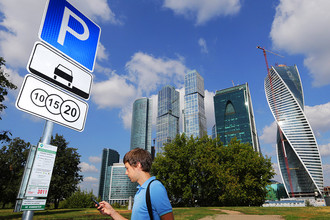 Житель города во время оплаты парковки с помощью мобильного телефона на платной парковке