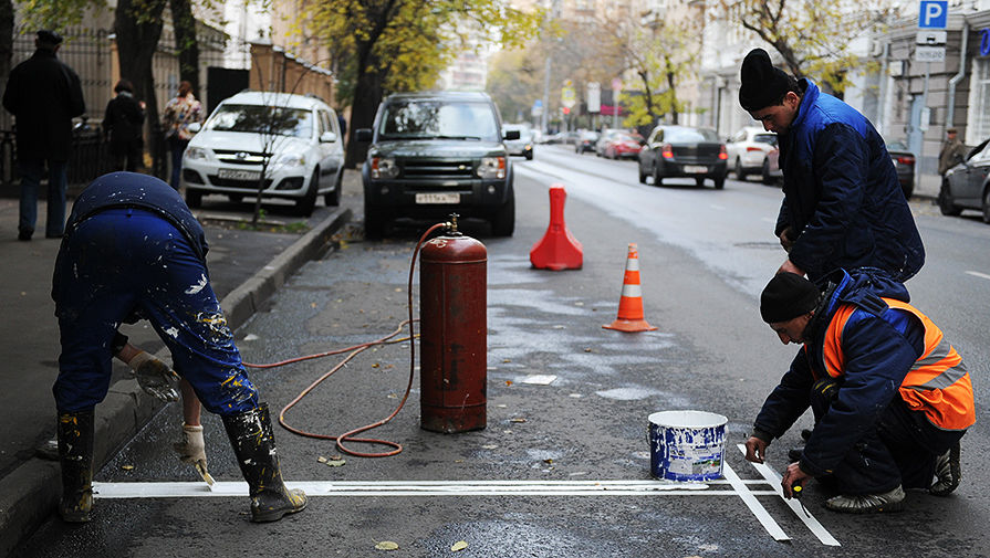 Рабочие наносят новую дорожную разметку для парковки на одной из улиц города