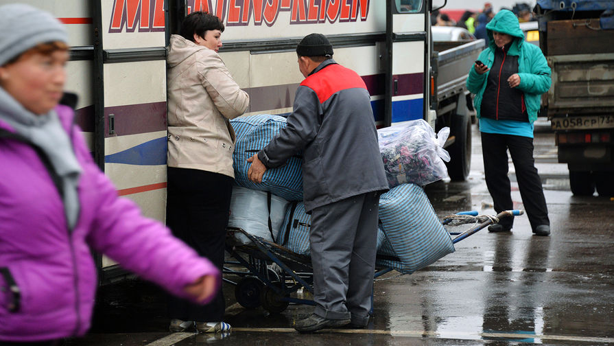 Торговцы у междугороднего автобуса на территории торгового центра «Садовод» в Москве.