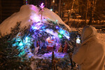 Девушка фотографирует Рождественский вертеп, созданный в снежном сугробе, во время ночной Рождественской службы в Знаменском православном храме в Дивногорске