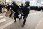 Полицейские несут потерявшего сознание коллегу во время столкновений с протестующими, Париж, 13 апреля 2023 года