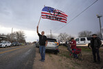 Мужчина с флагом в поддержку политика Дональда Трампа и против миграционной политики Джо Байдена в ожидании автопробега «Верните нашу границу» в Кемадо, штат Техас, 2 февраля 2024 года
