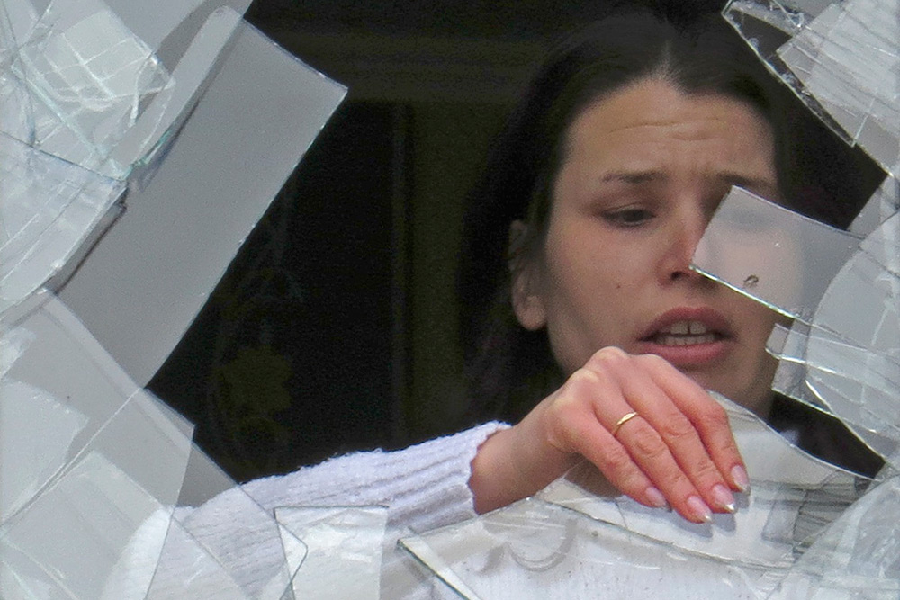 Медработница разбирает завалы в кабинете 27-й больницы, где в результате попадания снаряда пять человек погибли