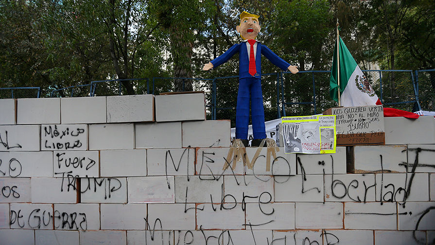 Импровизированная стена и пиньята в виде президента США Дональда Трампа во время протеста около американского посольства в Мехико, 20 января 2017 года