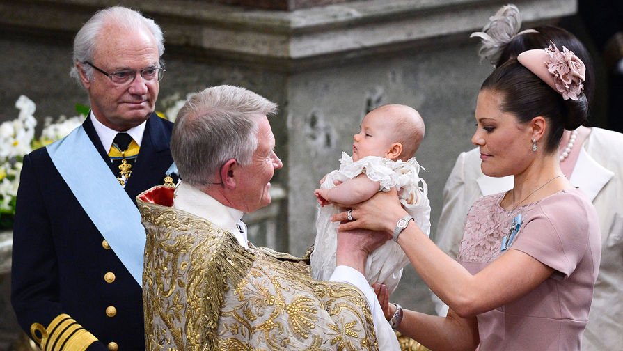 Король Швеции Карл XVI Густав, архиепископ Андерс Вейрюд и кронпринцесса Виктория с дочерью Эстель во время торжественной церемонии в Стокгольме, 2012 год