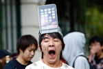 Мужчина с макетом модели iPhone 6 Plus на голове стоит в очереди токийского Apple Store