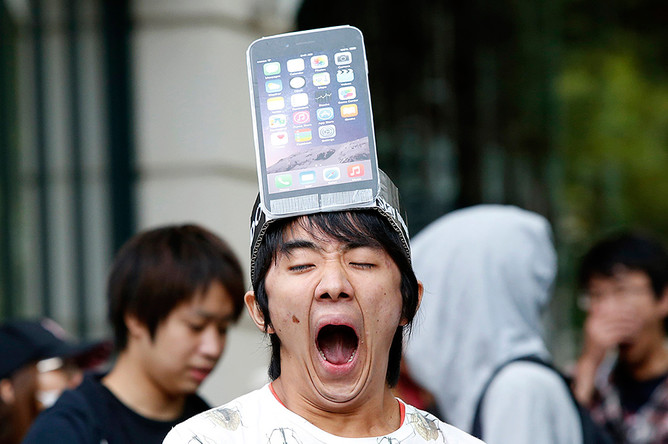 Мужчина с макетом модели iPhone 6 Plus на голове стоит в очереди токийского Apple Store