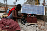 Женщина заряжает мобильный телефон от солнечной панели. Жереми, Гаити