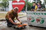 Местный житель, получивший хлеб, на одной из улиц в селе Чернобаевка, Херсонская область, Украина, 25 июля 2022 года