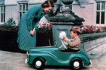 Королева Елизавета II и принц Чарльз на игрушечном автомобиле во дворе замка Балморал, 1952 год