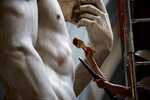 Реставратор счищает пыль со статуи Давида Микеланджело в Академии изящных искусств во Флоренции, 25 сентября 2023 года