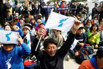 Жители Южной Кореи с флагами, символизирующий единую Корею, недалеко от деревни Пханмунджом, где проходит встреча северокорейского лидера и южнокорейского президента, 27 апреля 2018 года