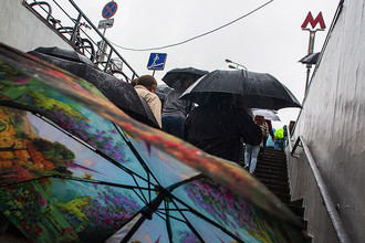 Люди выходят из подземного перехода Московского метрополитена во время дождя в Москве