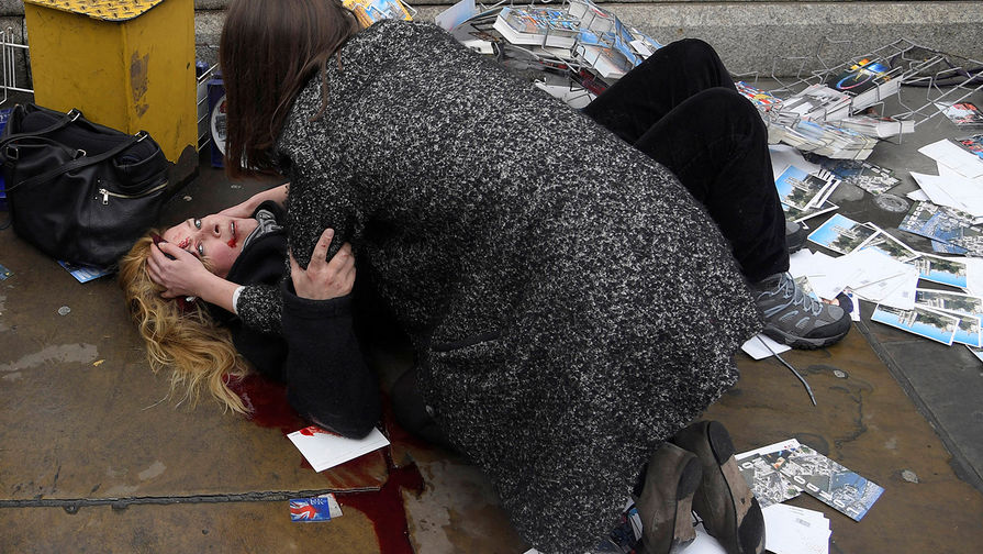 Прохожая успокаивает девушку, раненную во время теракта на Вестминстерском мосту в Лондоне — тогда террорист Халид Масуд на грузовике въехал в толпу людей; пять человек погибли, еще несколько были ранены