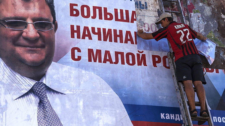 Рабочий расклеивает в Донецке предвыборный плакат кандидата на пост главы города Игоря Мартынова 
