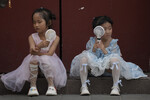Дети спасаются от жары с помощью электрических вентиляторов на улице в Пекине, Китай, 25 июня 2023 года