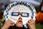 Ребенок наблюдает за частичным солнечным затмением с помощью самодельной маски в Нью-Йоркском зале науки в районе Квинс, Нью-Йорк, США, 8 апреля 2024 года 