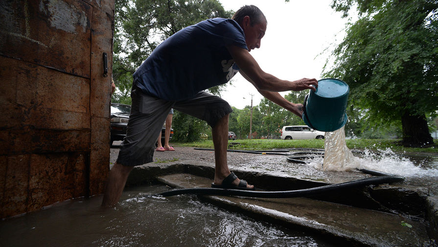 Мужчина вычерпывает воду из&nbsp;подъезда на&nbsp;затопленной улице Уссурийска