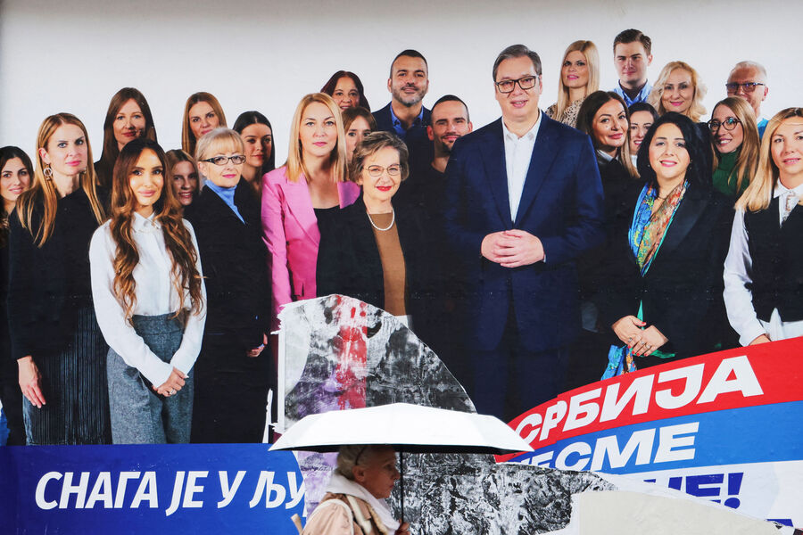 Женщина проходит мимо предвыборного рекламного щита, на котором изображен президент Сербии Александар Вучич с членами его правящей Сербской прогрессивной партии в Белграде, Сербия, 14 декабря 2023 года